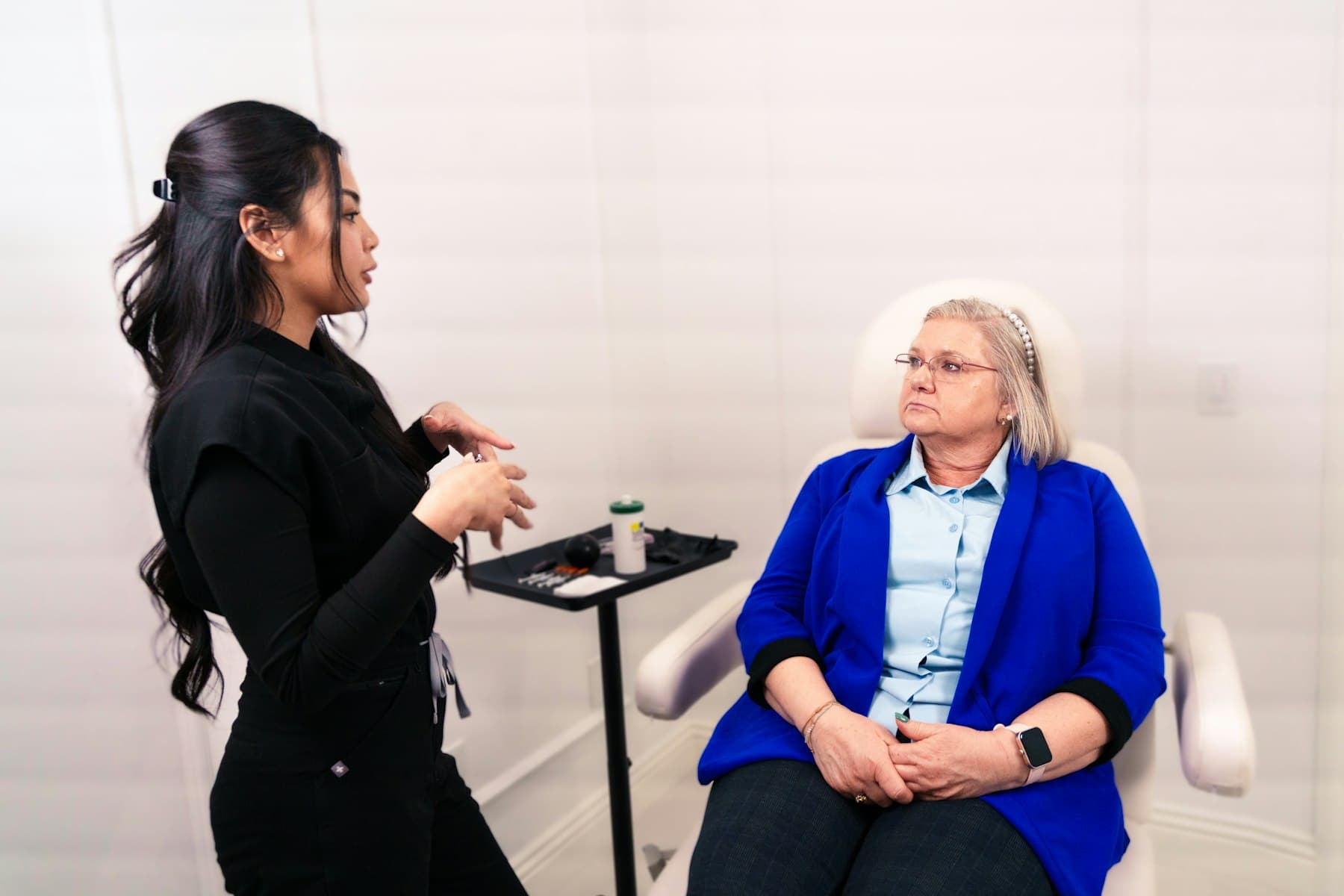 An aesthetic practitioner talking with a client seated in a treatment chair.