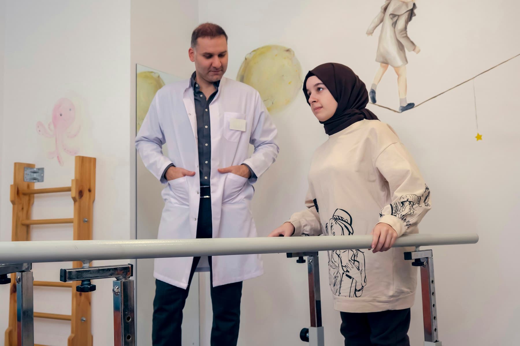 A physical therapist guiding a patient at parallel bars.