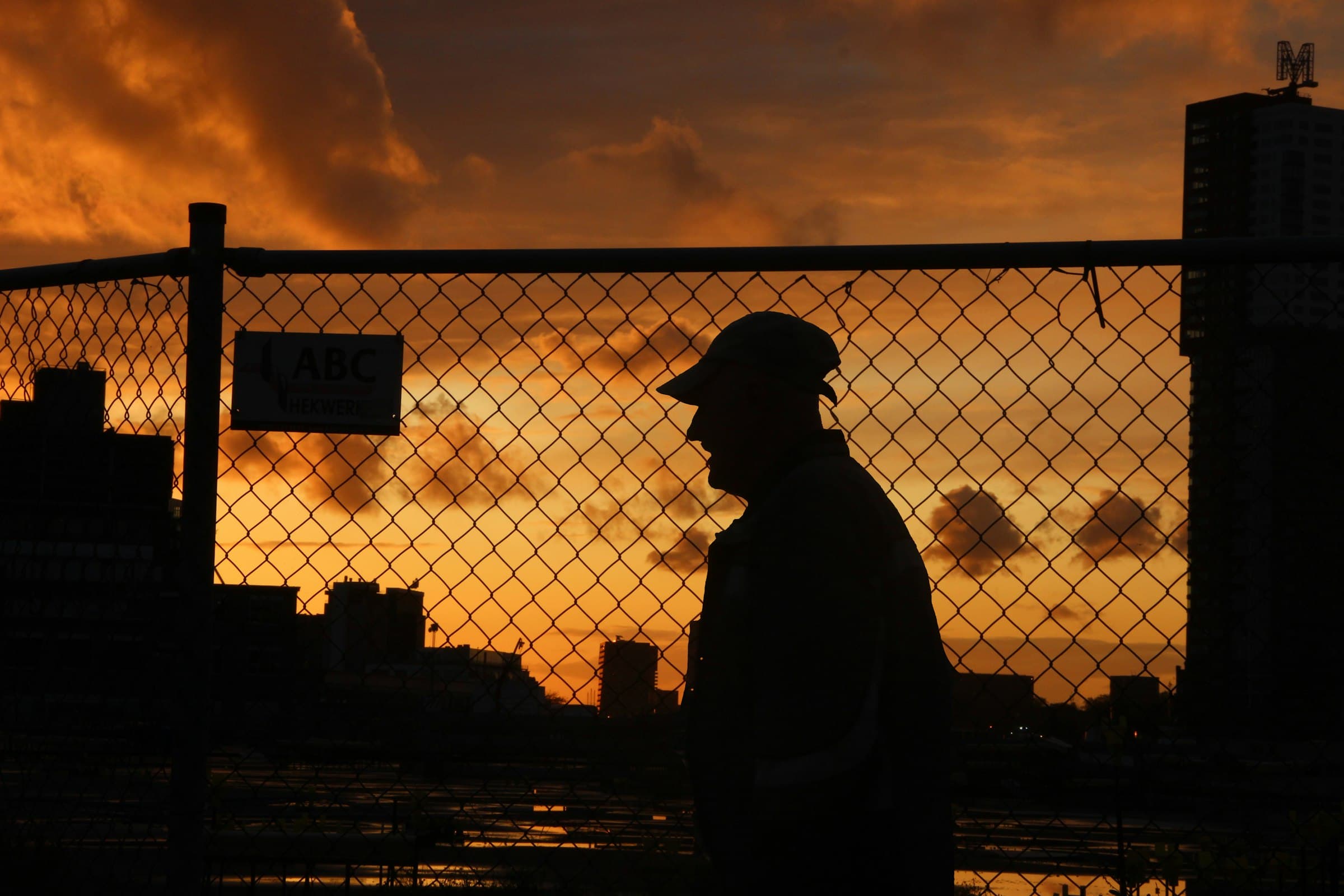 A man in a cap looks out over a city at dusk.