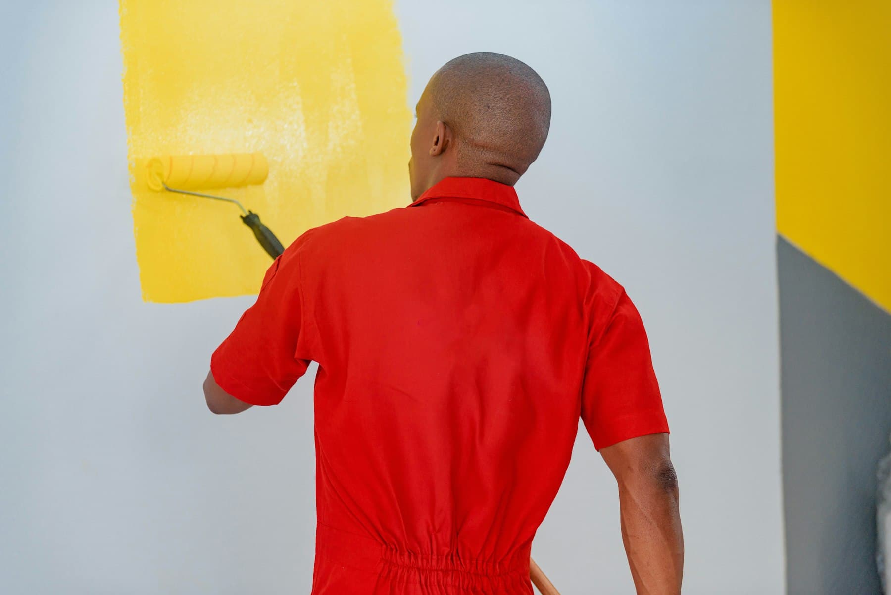 A painter rolling fresh paint onto a wall.